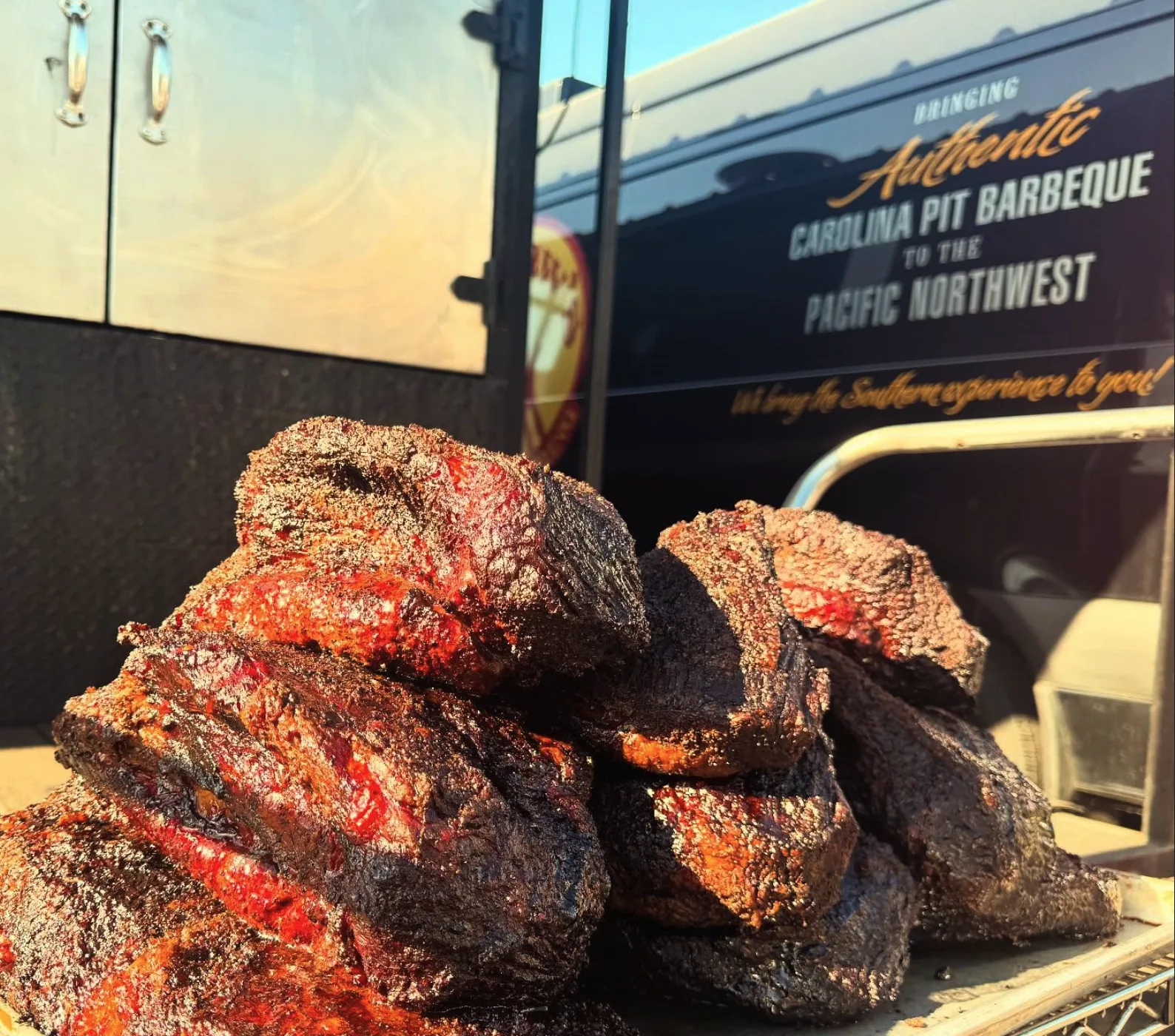 Smoked beef brisket on a rack in front of the Philyaw's catering van.